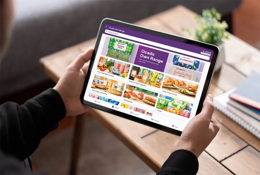 A picture of someone holding a tablet and interacting with the ocado moible app